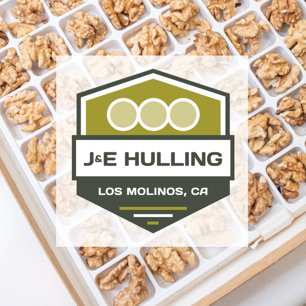 J & E Hulling logo over a blurry photo of walnuts